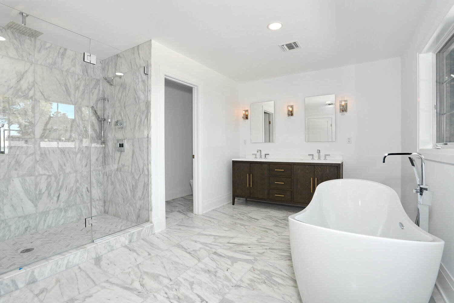 Primary bathroom with marble shower and freestanding tub by Dadak LLC in River Vale NJ