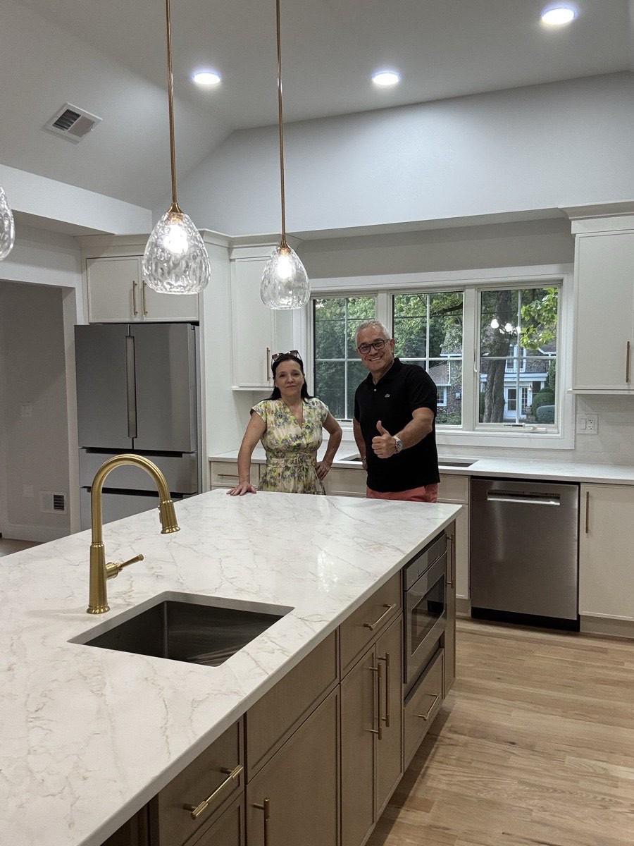 Dragan and Kosa Dinic in the finished kitchen of a custom home in Hillsdale, NJ, with a marble waterfall island and gold fixtures, built by Dadak LLC
